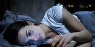 Woman lying in bed looking at a smartphone