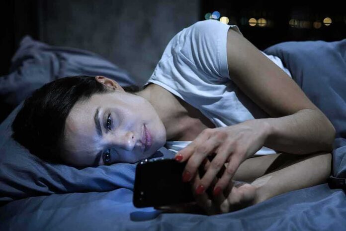Woman lying in bed looking at a smartphone