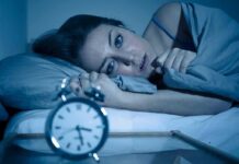 Insomnia Gap Exposed—Why Women Are Hit Harder Woman lying awake in bed beside an alarm clock