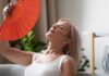 Woman fanning herself with an orange hand fan