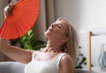 Woman fanning herself with an orange hand fan