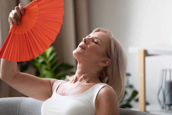 shutterstock_1504807925 Woman fanning herself with an orange hand fan