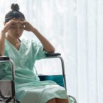 Woman in a wheelchair holding her head