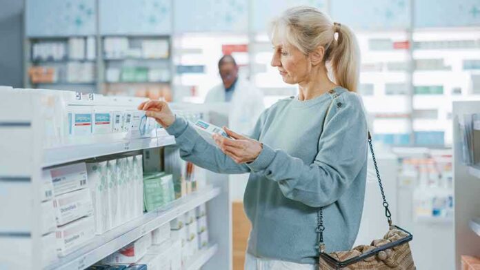 shutterstock_1999646099 Woman shopping for medicine in a pharmacy aisle