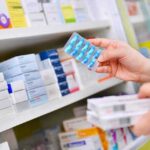 pharmacist holding blister pack of blue capsules