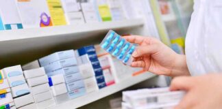 pharmacist holding blister pack of blue capsules