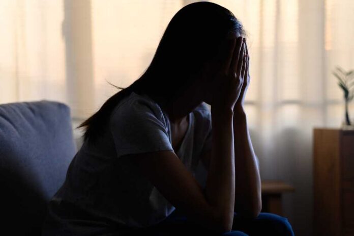 Silhouette,Photo,Of,Young,Asian,Woman,Feeling,Upset,,Sad,,Unhappy A silhouette of a person sitting with their head in their hands, conveying distress