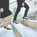 Two businesspeople in formal wear walking up stairs