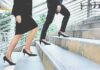Two businesspeople in formal wear walking up stairs