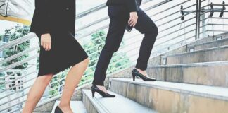 Two businesspeople in formal wear walking up stairs