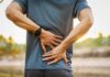 Person holding lower back in pain outdoors