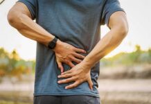 Person holding lower back in pain outdoors