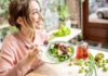 Healthy Staples Linked To Gut Flares Woman eating a fresh salad at a bright cafe