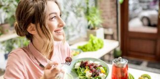 Woman eating a fresh salad at a bright cafe