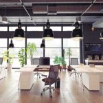 Modern open-plan office with desks, chairs, and large windows