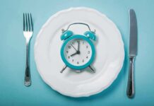 Effect of Time-Restricted Eating on Adults with Diabetes Alarm clock on a white plate with fork and knife