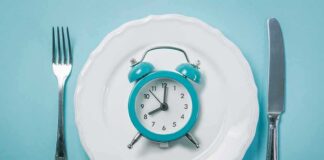 Alarm clock on a white plate with fork and knife