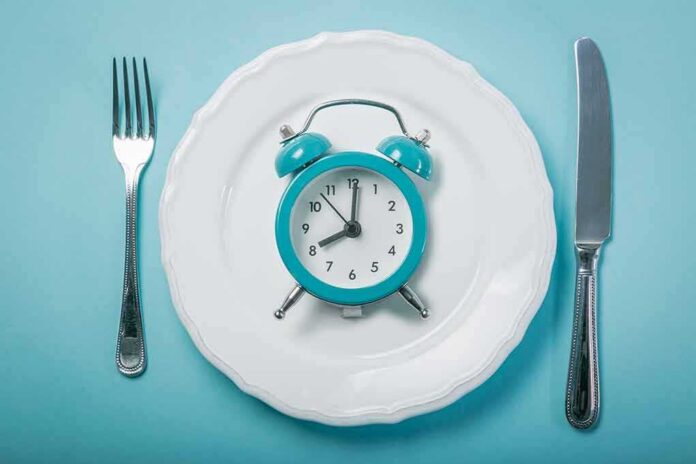 shutterstock_1036153894 Alarm clock on a white plate with fork and knife