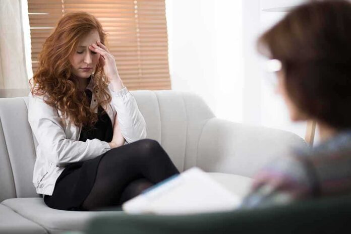 Woman with hand on forehead sitting on couch during counseling session