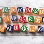 Wooden alphabet blocks scattered on a white wooden surface