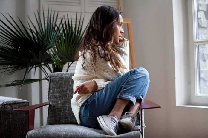 Woman sitting curled up on a chair looking out a window