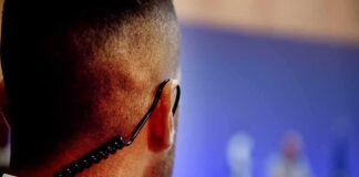 Security guard with earpiece watching a blurred event stage