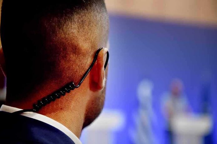 Security guard with earpiece watching a blurred event stage