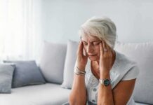 Silent Deficiency Supercharges Depression Risk Older woman sitting on a couch holding her temples