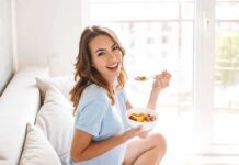 Eat This, Watch Age Markers Tumble Woman sitting on a couch eating a bowl of fruit salad
