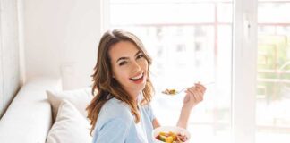 Woman sitting on a couch eating a bowl of fruit salad