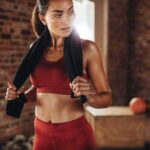 Woman in red workout clothes holding a towel in a gym