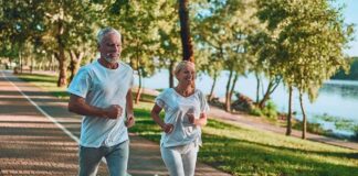 Two adults jogging on a tree-lined lakeside path