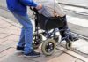 Caregiver pushing person in wheelchair over curb