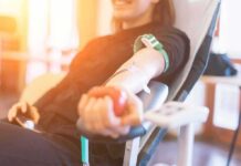 Person donating blood while squeezing a red ball