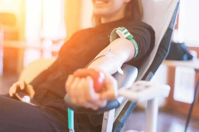 Person donating blood while squeezing a red ball