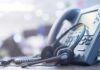 Outdated 911 Gear Endangering Millions? Headset resting on an office desk phone