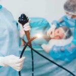 Medical staff preparing endoscope near patient on hospital bed