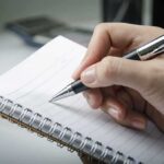 Rewire Your Addiction Now — Insights from Cognitive Neuroscience A hand holding a pen above a blank notebook page