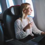 How to get rid of travel bloating: Tips for relief Passenger with headphones seated by airplane window