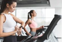 Woman on treadmill checking smartwatch in gym