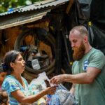 Volunteers distribute relief supplies to a woman outdoors