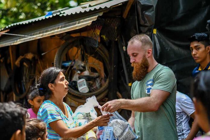 Volunteers distribute relief supplies to a woman outdoors
