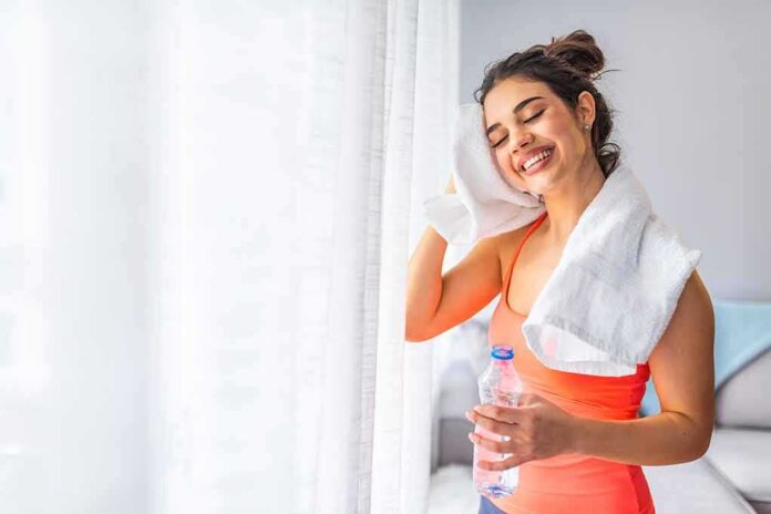 shutterstock_1436224892 Woman wiping sweat with towel after workout