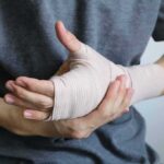 Person holding a hand wrapped in an elastic bandage