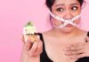Mindful Eating Interventions for Weight Loss Management Woman with measuring tape over mouth holding a decorated cupcake