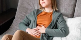 Person reclining on a couch with hands on stomach