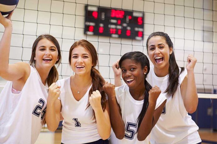 Members,Of,Female,High,School,Volleyball,Team Four female volleyball players celebrating in a gymnasium