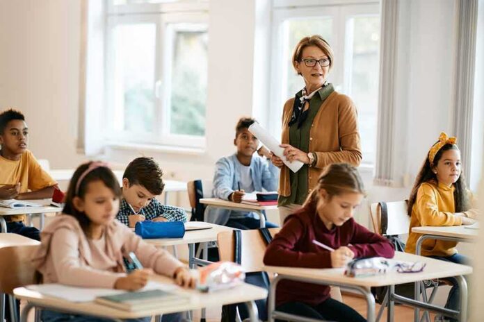 shutterstock_2144682361 Teacher standing among students in a bright classroom