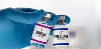 Gloved hand holding estrogen and testosterone vials