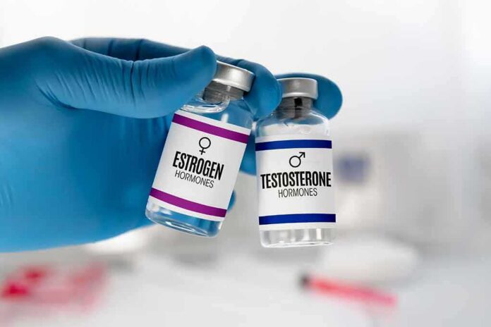 shutterstock_2237187075 Gloved hand holding estrogen and testosterone vials
